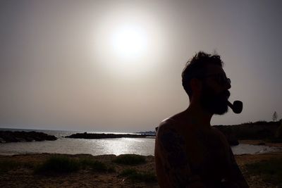 Man in sea against sky during sunset