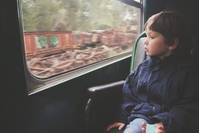Boy looking out through window while traveling in train