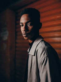 Side view of young man standing against wall