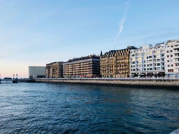 Buildings by sea against blue sky