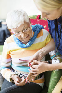 Female caretaker filing senior woman's fingernails at nursing home