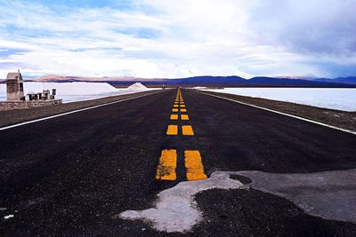 Road leading towards mountain against sky during winter