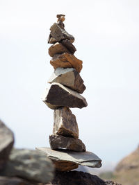 Stack of pebbles on rock against sky