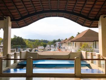 Chairs and tables in swimming pool against sky