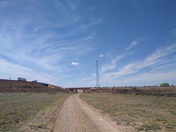 Road amidst field against sky