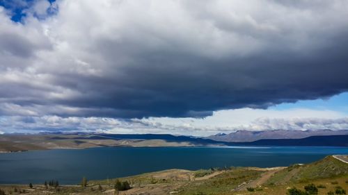 Scenic view of lake by mountains against storm clouds