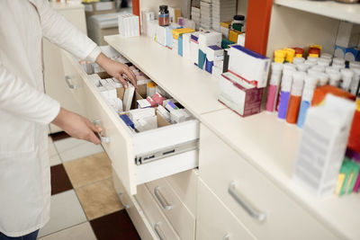 Pharmacist arranging medicines in drawer at pharmacy store