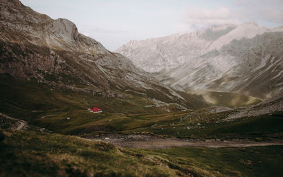 Scenic view of mountains against sky with house in the middle of them