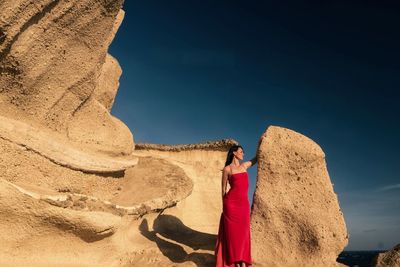 Woman standing on rock against sky