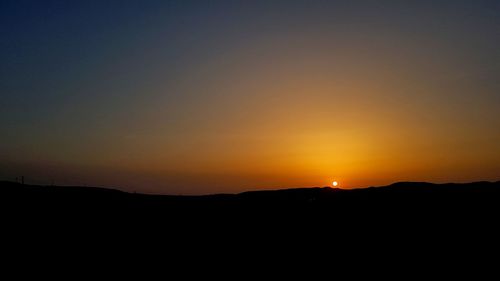 Scenic view of silhouette landscape against orange sky