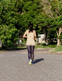 Rear view of woman running on road