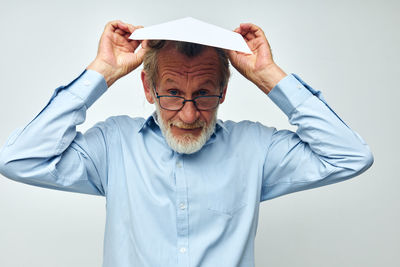 Portrait of senior man holding paper on head