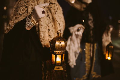 Midsection of people in costume holding illuminated lanterns