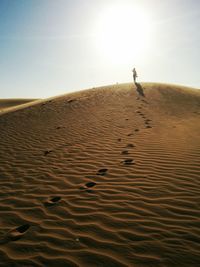 Person standing at desert against sky on sunny day