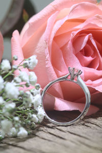 Close-up of pink rose and wedding ring on table