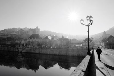 Scenic view of one person on bridge over river in city against sky