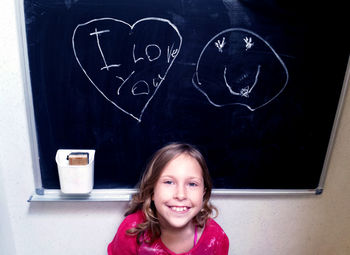 Message written on a chalk board and a beaming little girl who wrote it 