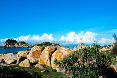 Panoramic view of rocks and sea against blue sky