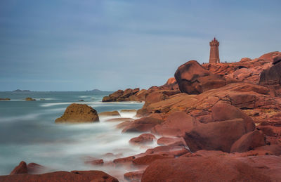 Rock formations on sea shore against sky