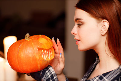 Young woman holding pumpkin in dark