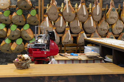 Red slicer and group of whole raw hams hung on a wall.