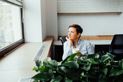 Side view of young man using mobile phone in office