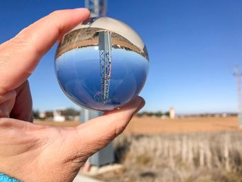 Close-up of person holding crystal ball against clear sky