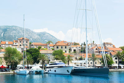 Sailboats moored on adriatic sea by houses against sky at cavtat