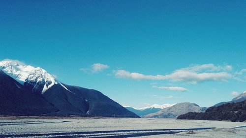 Scenic view of snowcapped mountains against blue sky