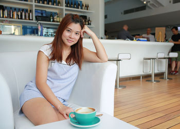 Portrait of woman sitting on sofa at cafe