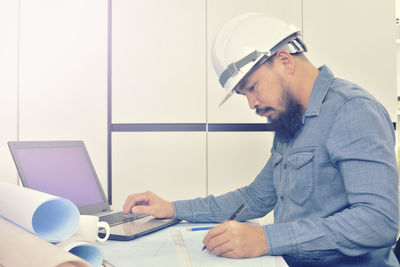 Side view of man working on laptop