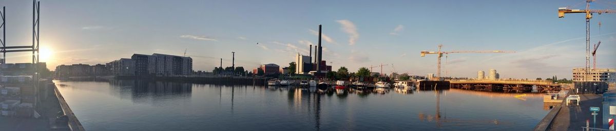 Panoramic view of river by buildings against sky at dusk