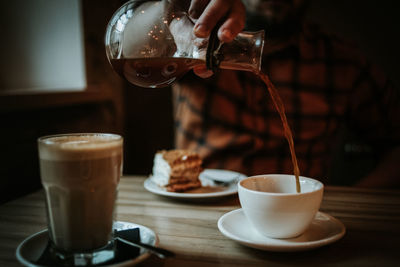 Close-up of coffee cup on table in cafe with cake on a background 