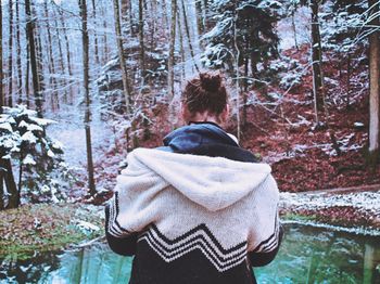 Rear view of woman standing on snow covered trees in forest