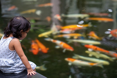 Girl sitting over fishes in lake