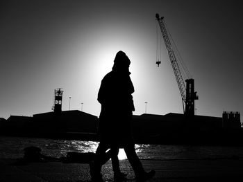 Silhouette man standing by sea against clear sky