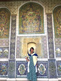 Portrait of smiling mid adult woman standing against patterned wall