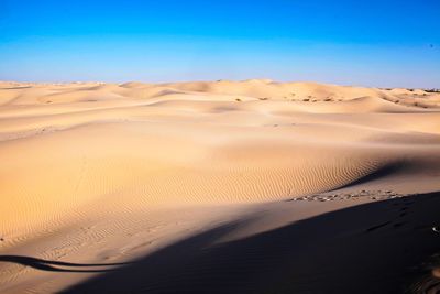 Sand dunes in desert against clear blue sky