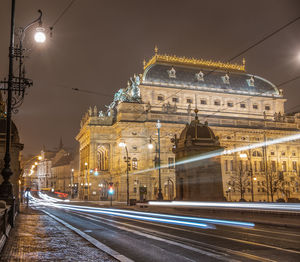 Light trails on road against buildings at night