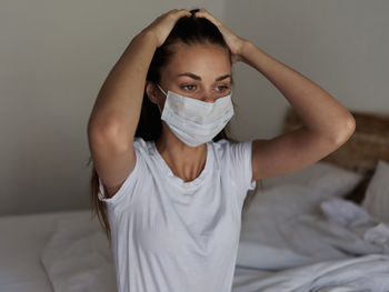 Young woman sitting on bed at home