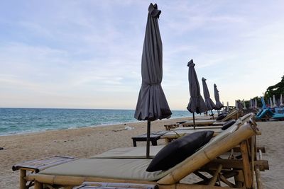 Chairs and tables on beach against sky