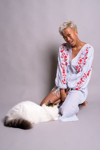 Full length of woman sitting against white wall