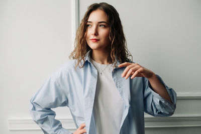 Portrait of young woman standing against wall