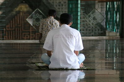 Rear view of man sitting on floor