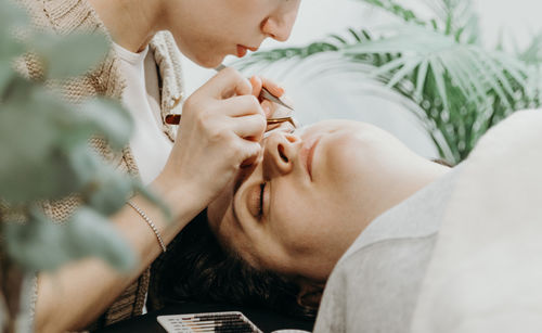 Portrait of a girl cosmetologist extending eyelashes to a woman.