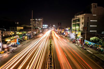 High angle view of light trails on road along buildings