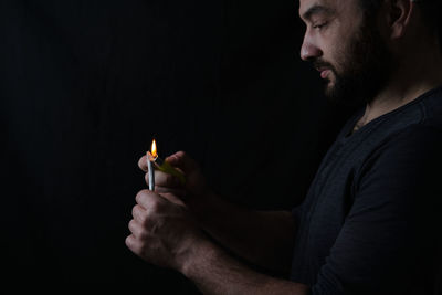 Side view of young man against black background