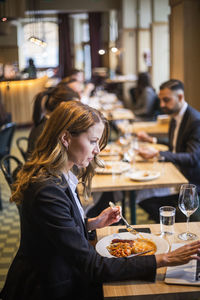 Side view of a woman sitting on table at restaurant