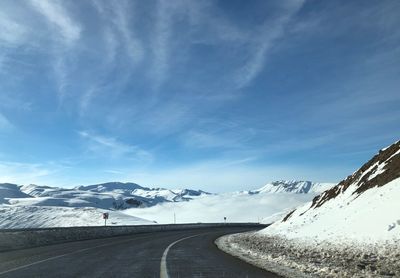 Road leading towards snowcapped mountains against sky