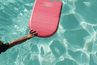 Cropped hand of child holding pool raft in swimming pool on sunny day